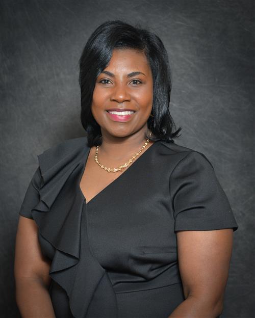 Katrina Collier Long's professional headshot; wearing a black dress against a grey background