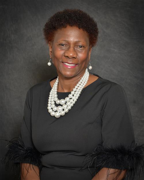 Florence Bellamy's professional headshot; wearing a black dress against a grey background