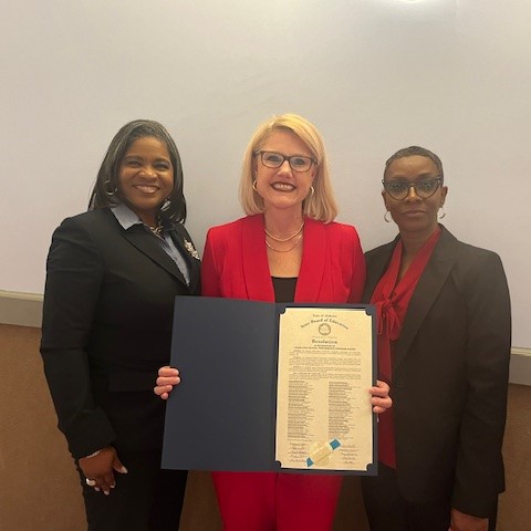  Dr. Sherrod, Mrs. Weston, and Mrs. Peterson smiling with a framed award.