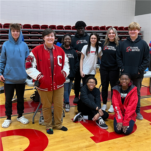 Nine robotics students stand together in gym for photo